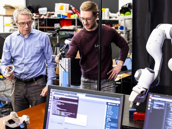 Professor Dieter Fox and a student demonstrate a remote operated robotic arm attempting to pick up a block