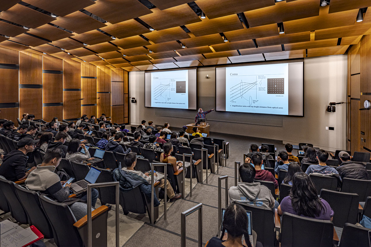 Photo of an Paul G. Allen School professor teaching class in an auditorium with large screens.