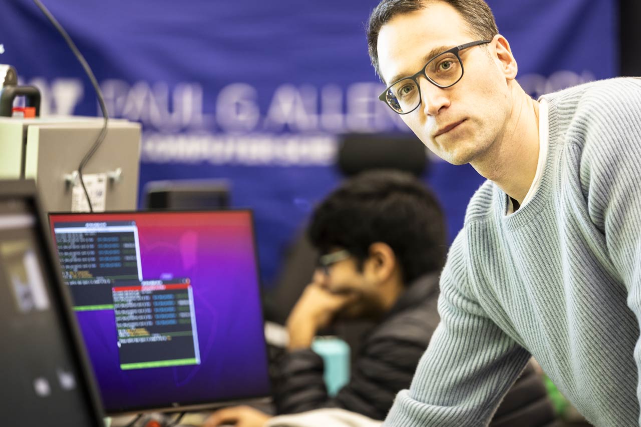 Markus Grotz, a Postdoctoral Scholar at the Allen school, looks up from a computer screen featuring research data to look at the camera.