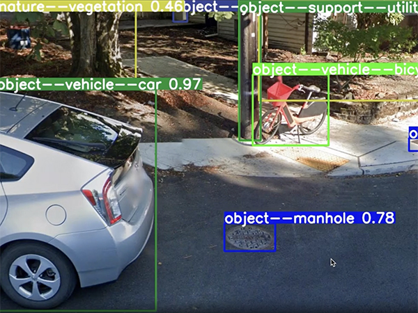 Street scene overlaid with color-coded object recognition labels for depicted car, bicycle, vegetation, utility pole, and manhole cover