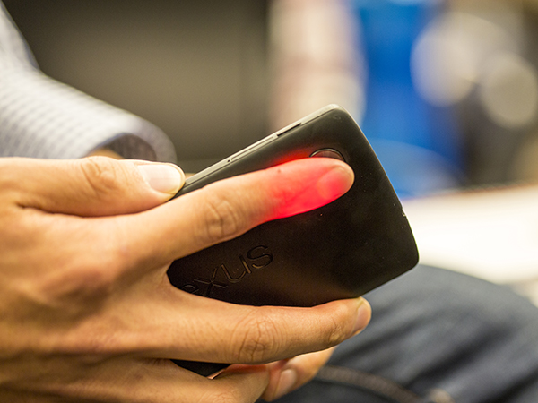 Closeup of a person's finger illuminated in red by smartphone camera