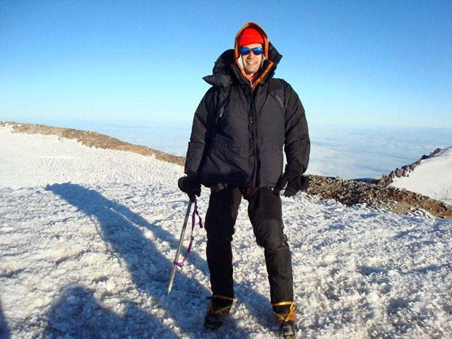 Photo of Kyril Faenov standing in the snow at the top of a mountain