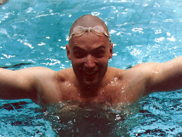 Photo of Kyril Faenov in a swimming pool, his arms stretched wide while smiling