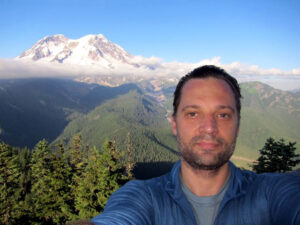 Photo of Kyril Faenov taking a selfie at the top of a mountain.