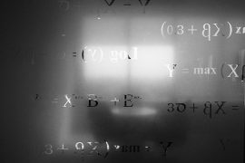 Silhouette of a table and chairs in front of a bright window that cases light on a frosted glass pane carved with math equations