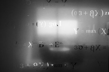 Silhouette of a table and chairs in front of a bright window that cases light on a frosted glass pane carved with math equations