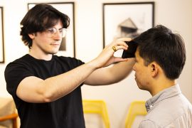 A person holding a smartphone against another person's forehead