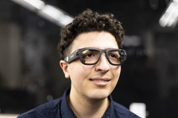 A person models specialized eye-tracking glasses with thick, dark frames