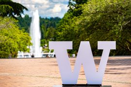 White UW block W statue on the brick of Red Square with Drumheller Fountain in the background